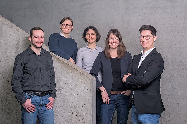 5 Personen an einer Betontreppe. Links und rechts stehen zwei junge Männer. In der Mitte befinden sich drei junge Frauen. Es handelt sich um die Mitarbeitenden der Präsenzstelle.