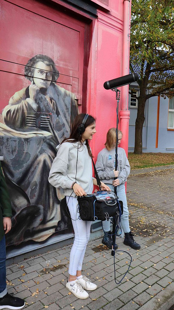 Ein Mädchen steht mit der Mikrofontechnik im Bild